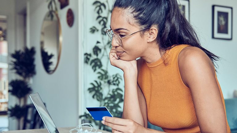 photo woman in apartment online shopping on laptop with credit card in hand