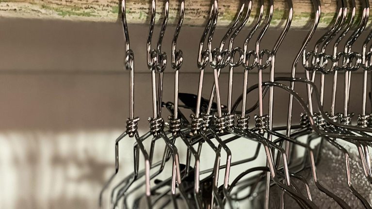 Empty metal clothing hangers in closet - stock photo