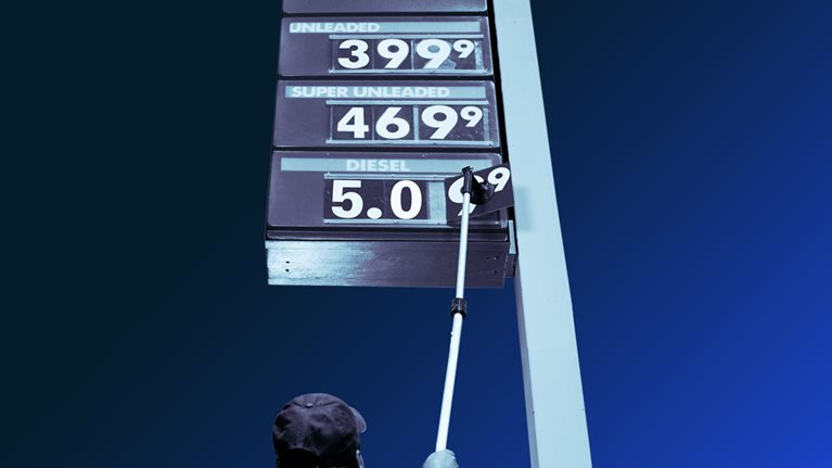 Man putting up price sign at station