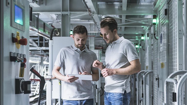 Two men in automatized high rack warehouse looking at tablet