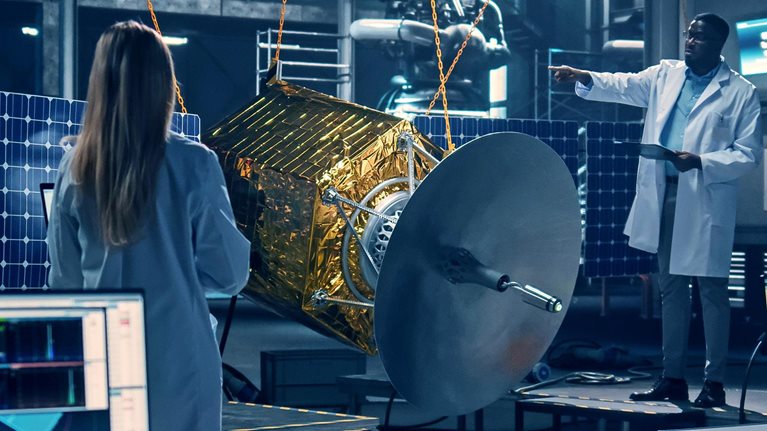 Diverse team of scientists using technological equipment and laptop computer to develop spacecraft for space exploration. - stock photo