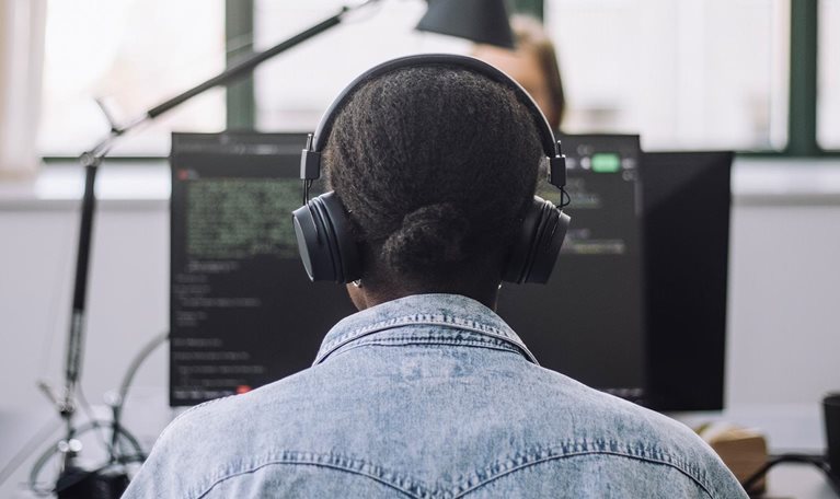 Rear view of female computer programmer coding on computer at desk in office - stock photo