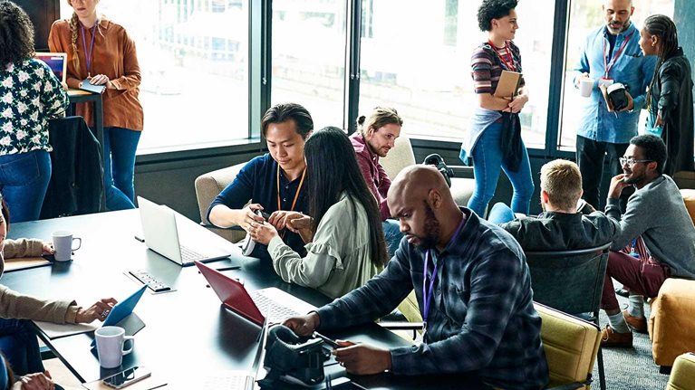 Multiple small groups of people working and congregating in a large office space