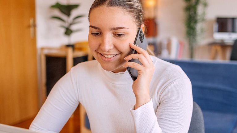 Young woman making on line order from home using mobile phone and laptop - stock photo