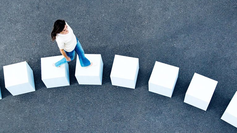 An aerial view of a woman walking across line of giant white cube