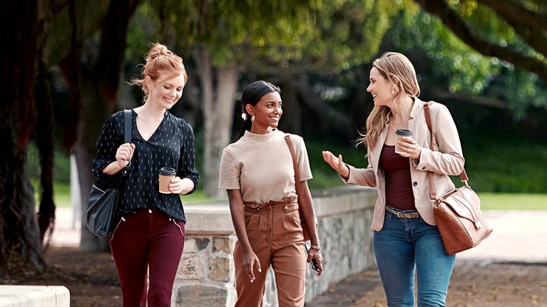 Shot of a group of young businesspeople chatting while walking through the city