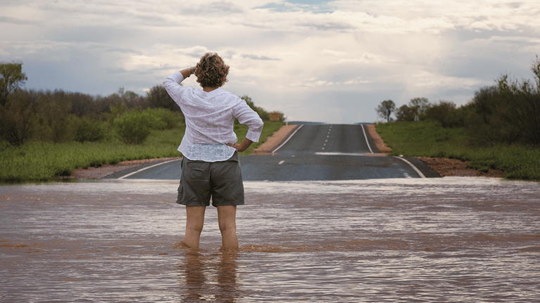 Woman stands in flooded street.