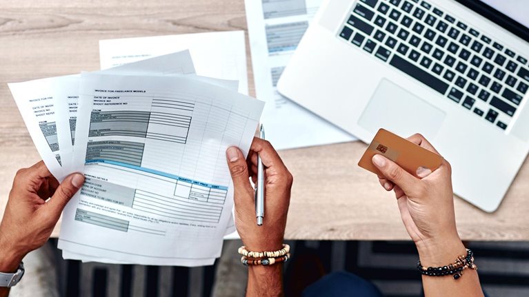 High-angle shot of a young using a credit card while going over their finances at home