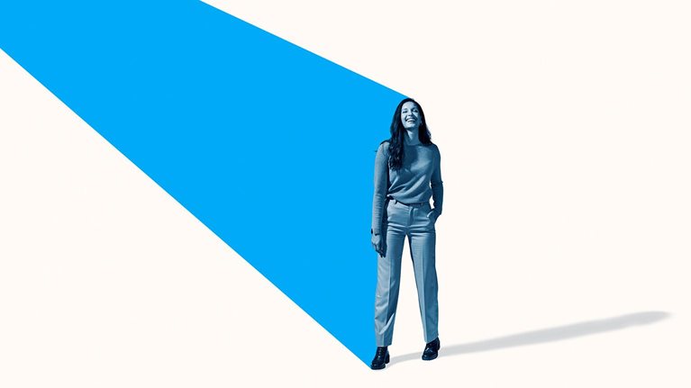 Full length image of a smiling woman standing with an angled turquoise beam