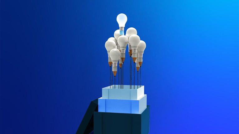 From the three stacked boxes protrudes a bouquet of about ten light bulbs, each with a base shaped like a pencil, leaving a distinct black line that resembles a flower stem. One bulb sits higher than the others, radiating a bright, glowing light.