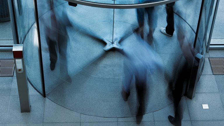 Blurry image of people walking through a revolving door