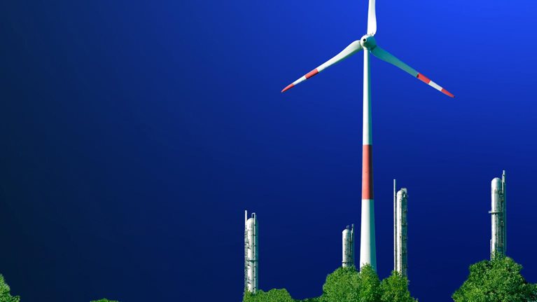 Wind turbine in front of a petrochemical installation