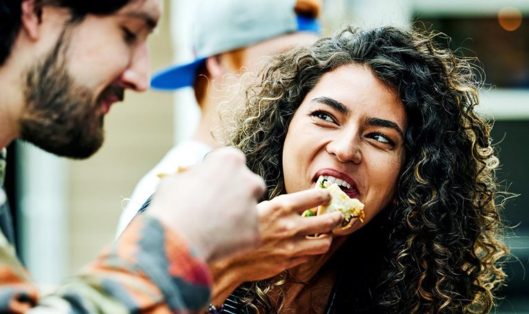 Medium close up shot of woman eating tacos with friends at food truck
