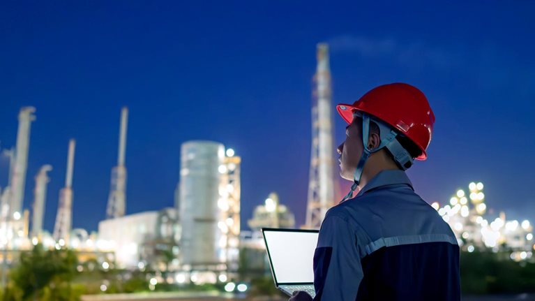 Chemical plant engineer using laptop at night