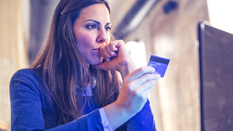 Image of a woman with a concerned look on her face shopping online and paying with card.