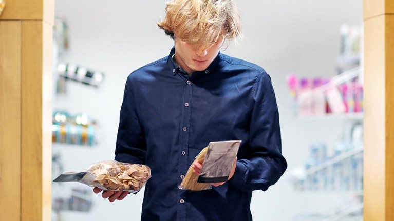 Teenager shopping in supermarket, reading product information