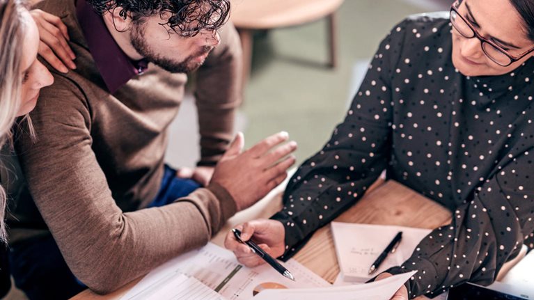 Overhead shot of couple sitting at table with female insurance agent