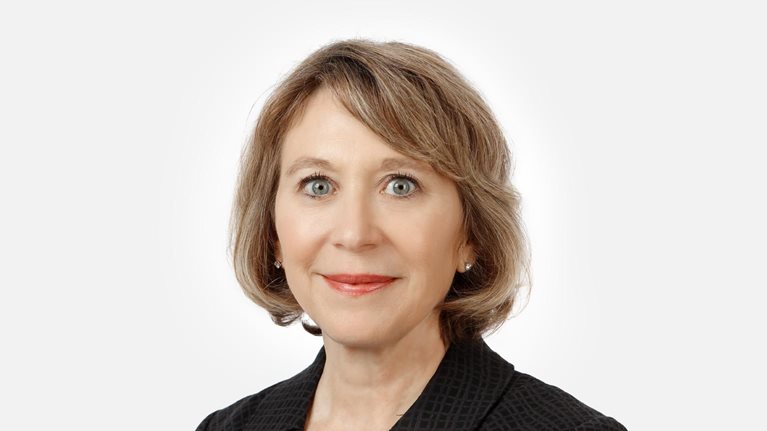 Portrait of a smiling Jayne Plunkett against a white backdrop.