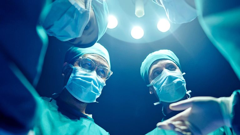 A group of surgeons wearing masks and performing surgery