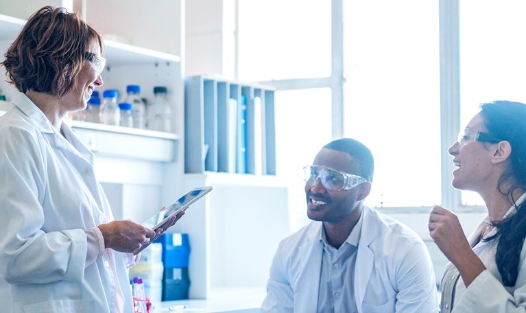Chemist using tablet PC while talking to coworkers