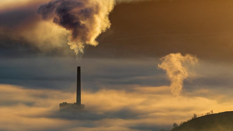 Hope valley and Castleton on a stunning misty morning with the pollution of the local cement factory at sunrise. Peak District National park. Derbyshire. - stock photo