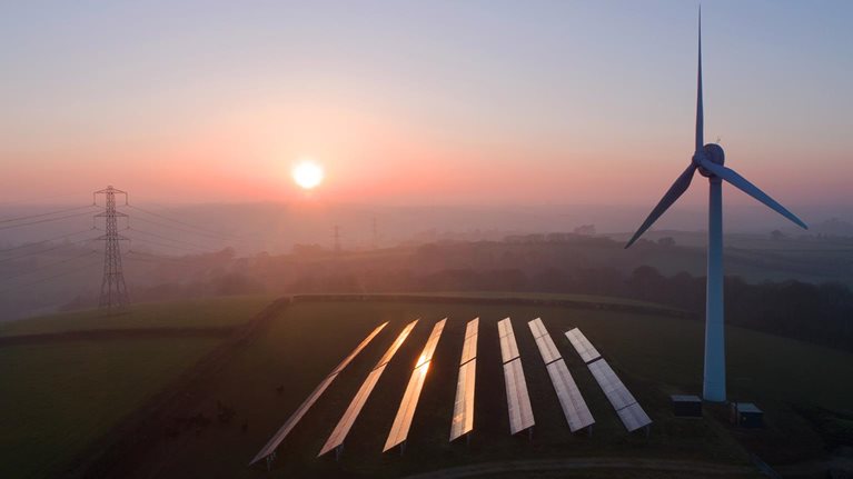 Solar panels and wind turbines in field - stock photo