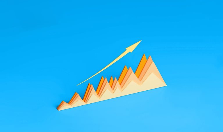 A three-dimensional graph made of paper displays a positive trend with its peaks and valleys. A gold arrow follows the upward trajectory of the graph against a vibrant blue background.