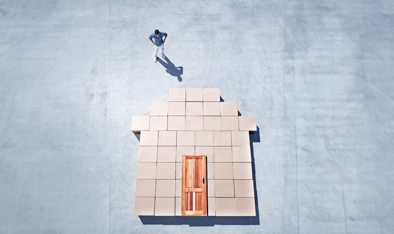 Man standing next to house outline on sidewalk - stock photo