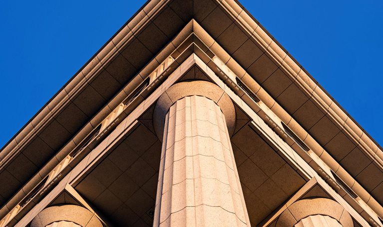 The exterior of a government building with large columns supporting the roof. The building is made of stone and has a classical architectural style.