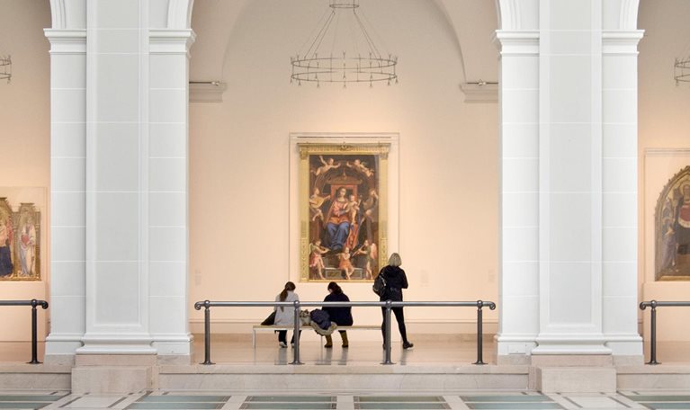 People view artwork along a hallway framed by three large arches in Brooklyn Museum’s Beaux-Arts Court.