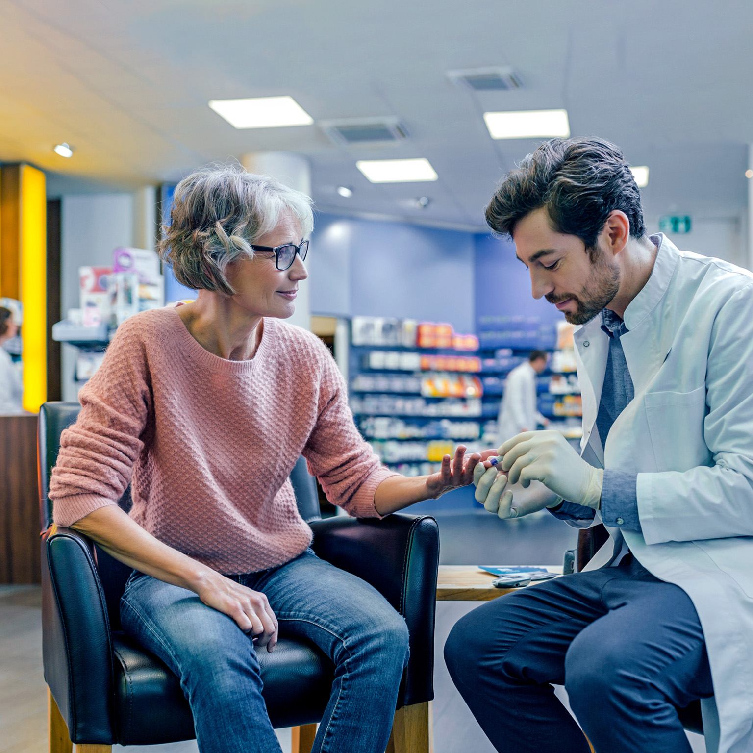 Pharmacist measuring blood sugar of customer in pharmacy