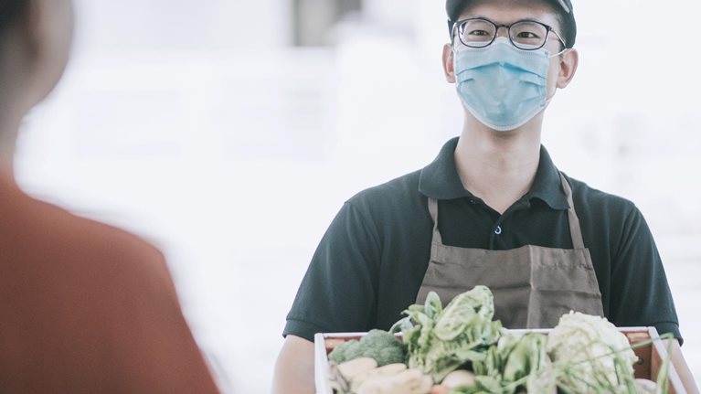 Delivery person handing over a box of vegetables to customer