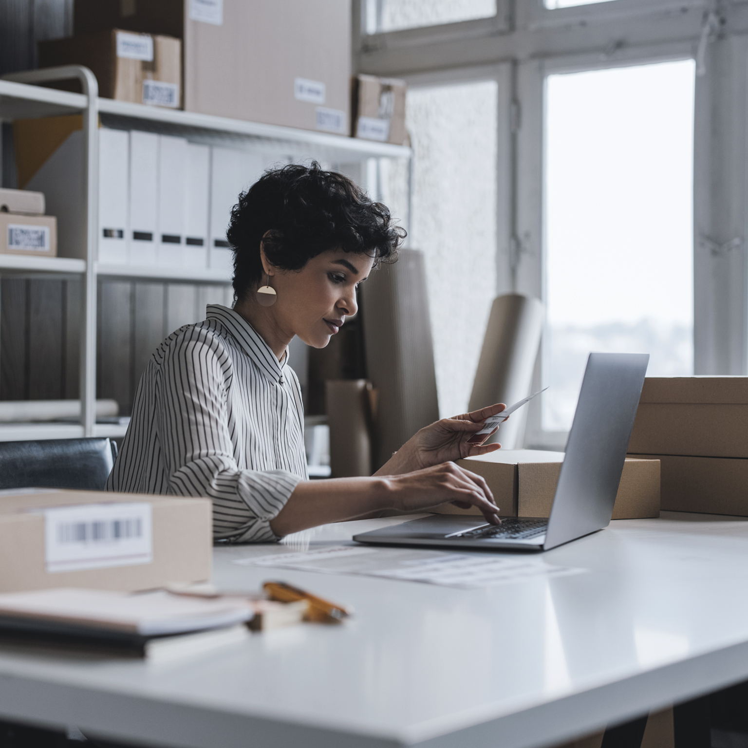  A young small business owner using her laptop to check the customer's order details on her website