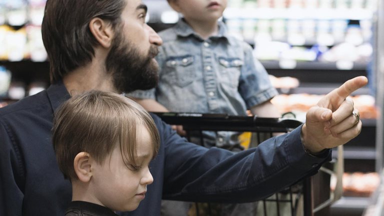 Father grocery shopping with his two children
