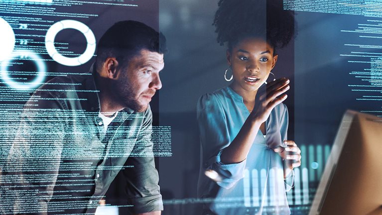 Shot of two programmers working together on a computer code at night - stock photo