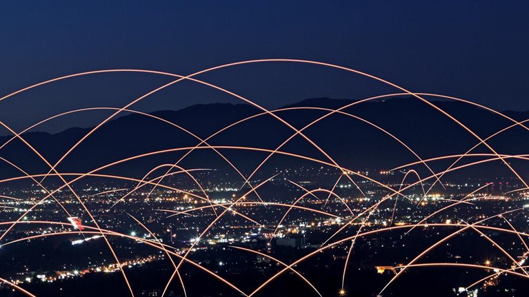 Multiple rays of light connecting buildings to each other across a city skyline