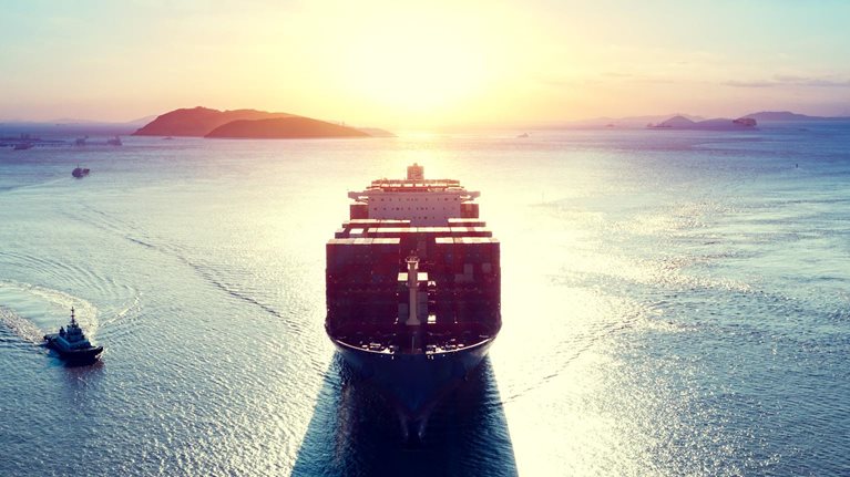 Cargo ship over sea at sunrise