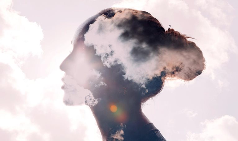 Illustration featuring a silhouette of a woman's head with a sunrise and cloud multiple exposure background.
