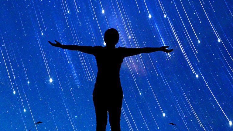 A girl standing with her arms open to a sky full of shooting stars